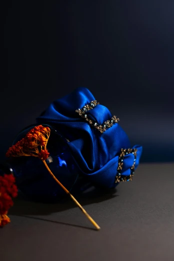 a blue flower sitting on top of a table, inspired by Jean Fouquet, baroque, silk belt, crystal clusters, rich colour, evening
