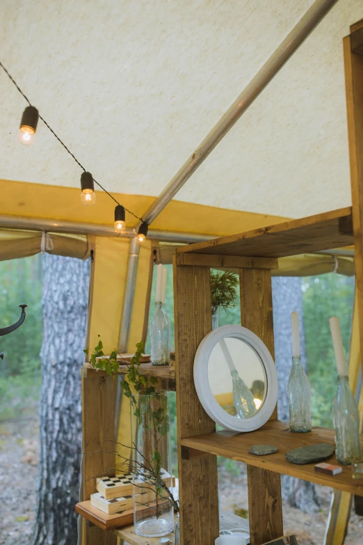 the inside of a tent with a table and chairs, by Jaakko Mattila, temporary art, yellow lanterns, forest details, wooden supports, detail studio quality lighting