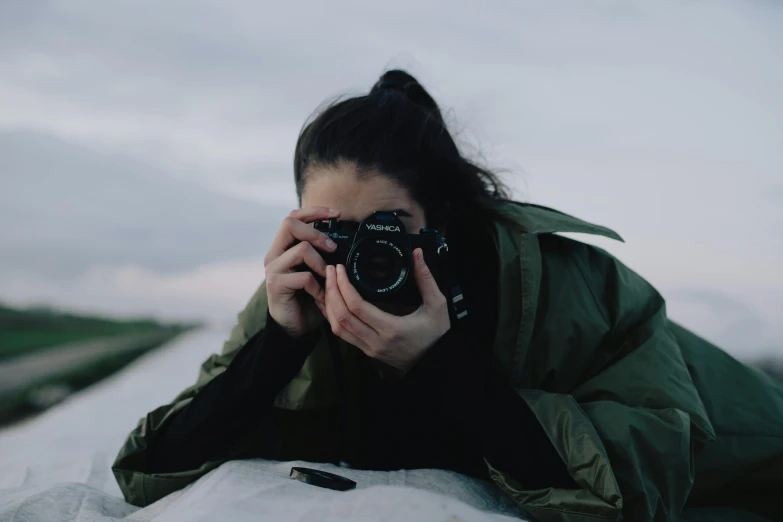 a woman taking a picture with a camera, a picture, pexels contest winner, black haired girl wearing hoodie, action shot girl in parka, unsplash transparent, over-shoulder shot