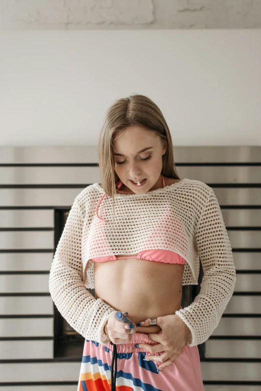 a beautiful young woman standing in front of a fireplace, a picture, unsplash, happening, pierced navel, teenage, mesh shirt, embarrassing