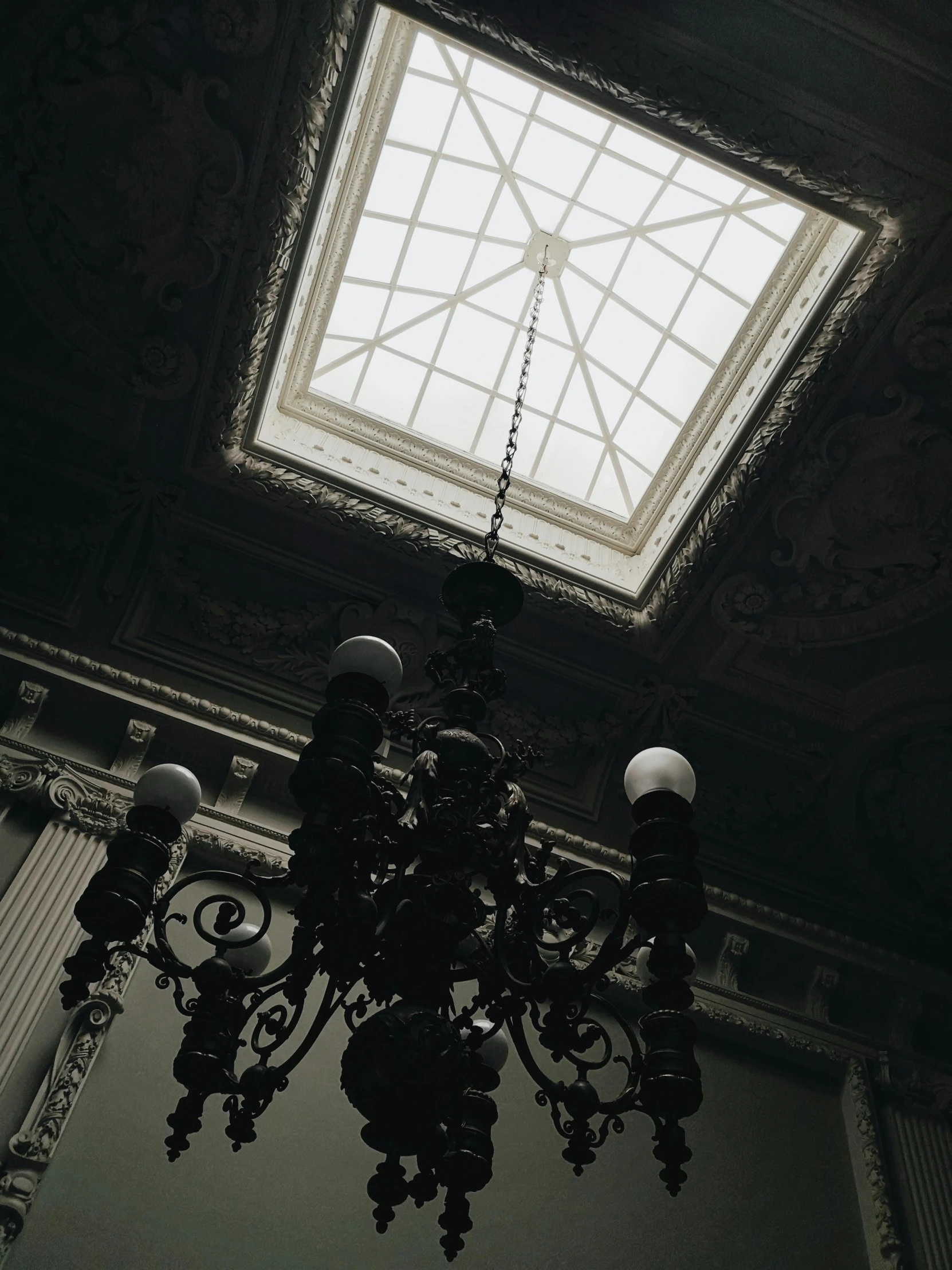 a black and white photo of a chandelier, inspired by Mihály Munkácsy, unsplash contest winner, neoclassicism, spooky mansion, skylights, dark and beige atmosphere, an aesthetic!