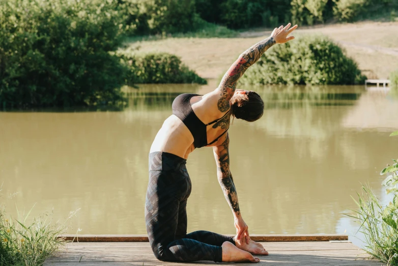 a woman doing a yoga pose on a dock, pexels contest winner, renaissance, body covered in floral tattoos, sydney park, arched back, naturalistic technique