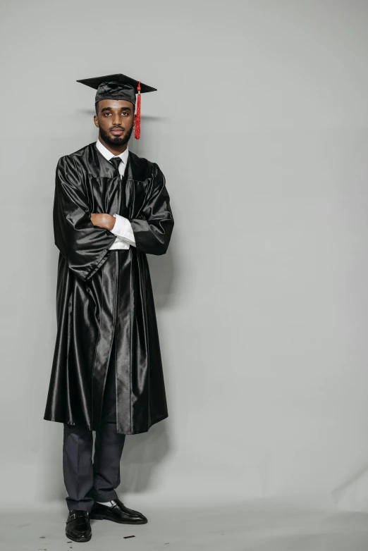 a man in a graduation gown posing for a picture, an album cover, by Ben Zoeller, pexels, black leather garment, black man, long gown, gray men