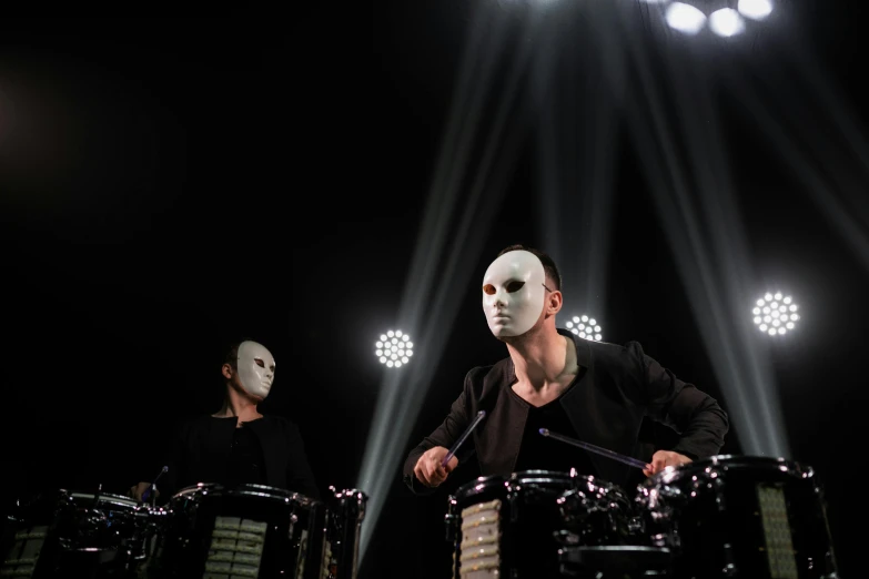 a group of men standing next to each other on a stage, an album cover, by Julia Pishtar, purism, with robotic parts on his face, bongos, with black metal face paint, shot with sony alpha