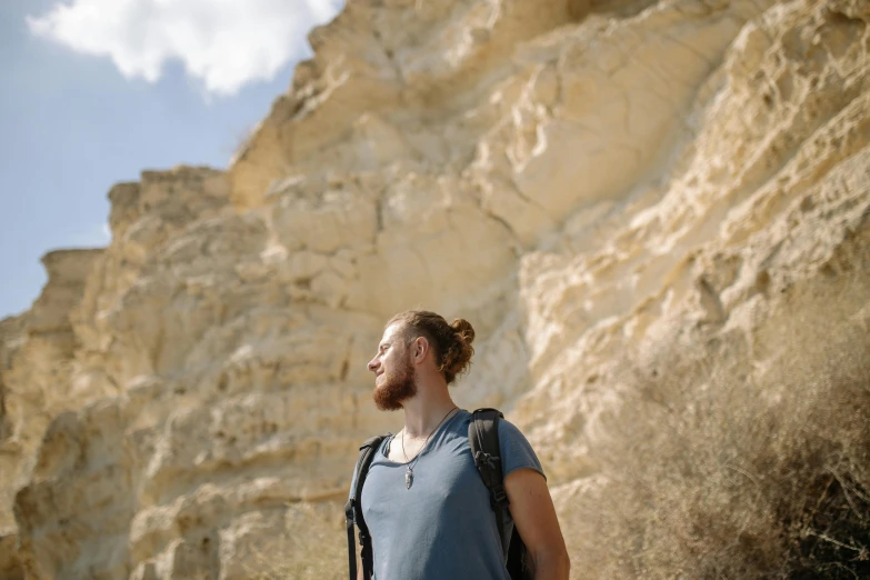 a man with a backpack standing in front of a cliff, a portrait, trending on pexels, renaissance, background image, gal yosef, high resolution image