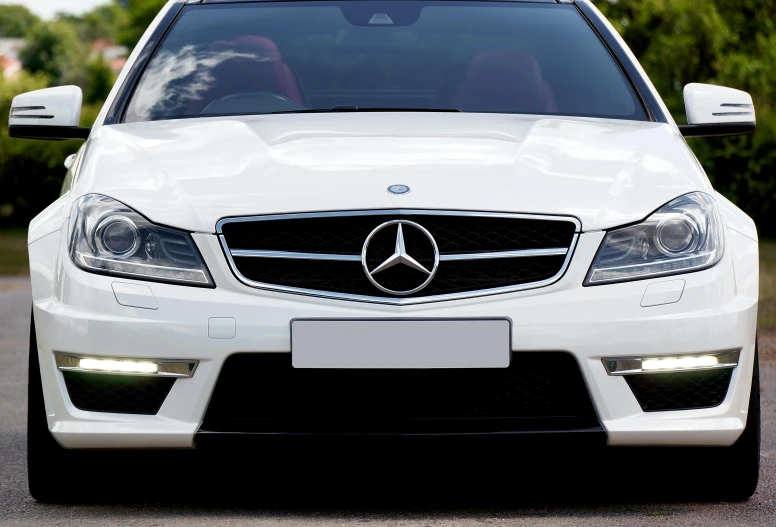 a white mercedes parked on the side of the road, trending on pixabay, custom headlights, transparent black windshield, front of car angle, hsv