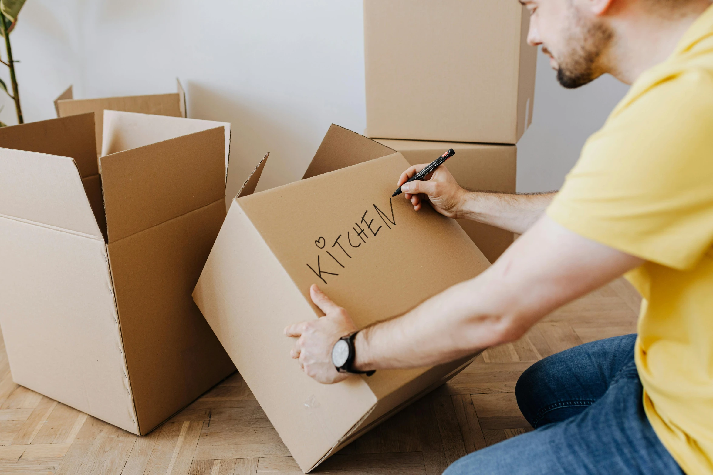 a man sitting on the floor writing on a box, a cartoon, by Everett Warner, pexels contest winner, package cover, melbourne, moving, maintenance photo