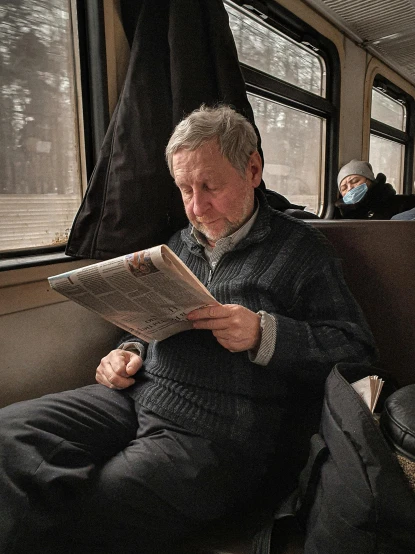 a man sitting on a train reading a newspaper, by Mstislav Dobuzhinsky, pexels contest winner, hyperrealism, gray haired, russia in 2 0 2 1, 🚿🗝📝