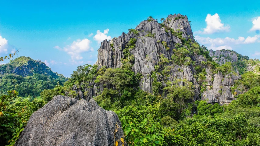 a large rock in the middle of a forest, by Reuben Tam, pexels contest winner, sumatraism, craggy mountains, limestone, panoramic, slide show