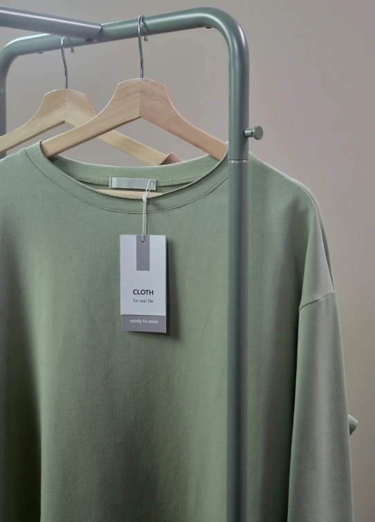 a green sweatshirt hanging on a clothes rack, gutai group, product label, muted colors with minimalism, goblin, zoomed in