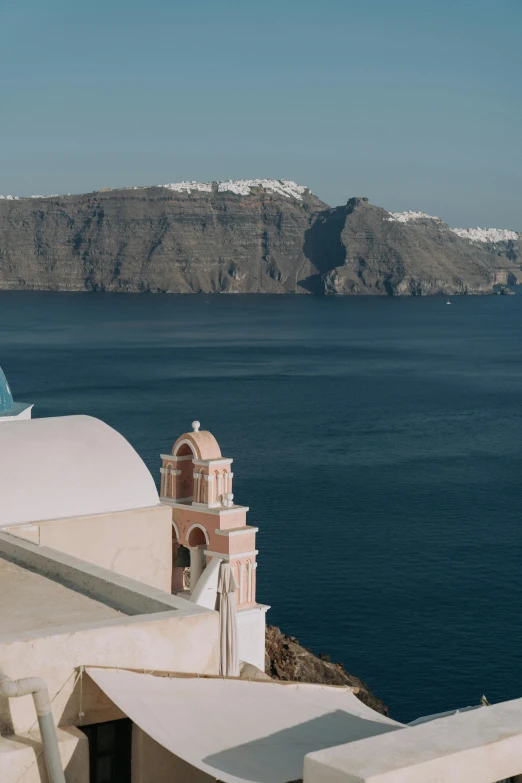 a man standing on top of a building next to the ocean, greek architecture, low quality photo, domes, she's sad