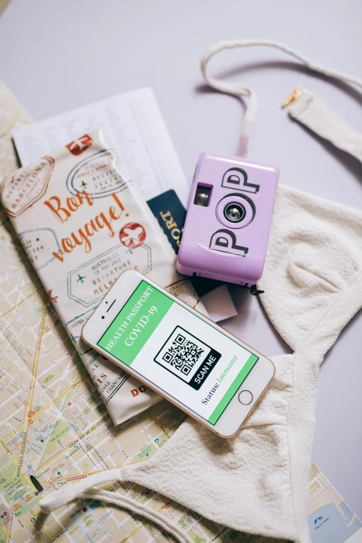 a couple of cell phones sitting on top of a map, a picture, by Julia Pishtar, happening, holding polaroid camera, green and pink colour palette, in suitcase, smartphone displays qr code