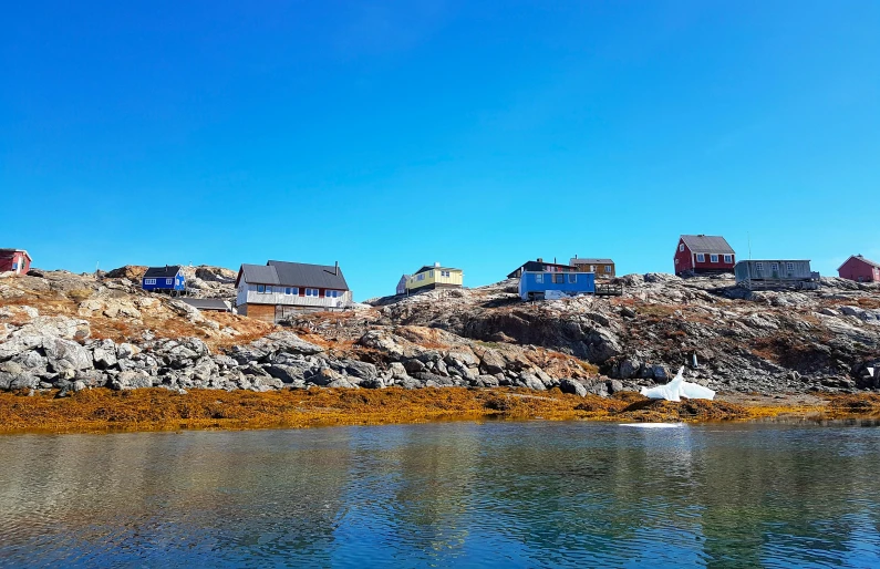 a boat sitting on top of a body of water, a photo, inspired by Wilhelm Marstrand, pexels contest winner, les nabis, white houses, inuk, light blue water, maple syrup sea