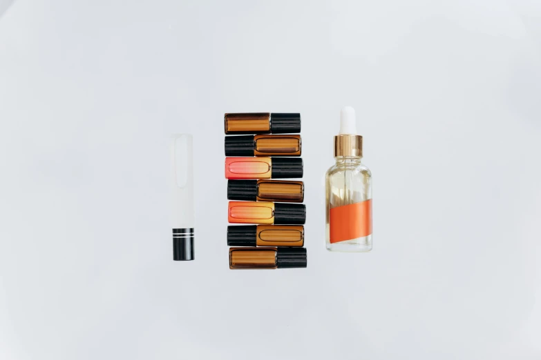 a bottle of perfume sitting on top of a white surface, a still life, inspired by Lubin Baugin, unsplash, pathology sample test tubes, orange and black, small nixie tubes, oil pastels and gold