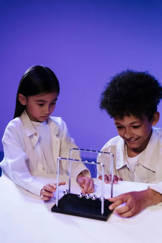 a couple of kids that are sitting at a table, kinetic art, wearing a lab coat, production photo, lights, mathematics unifying science