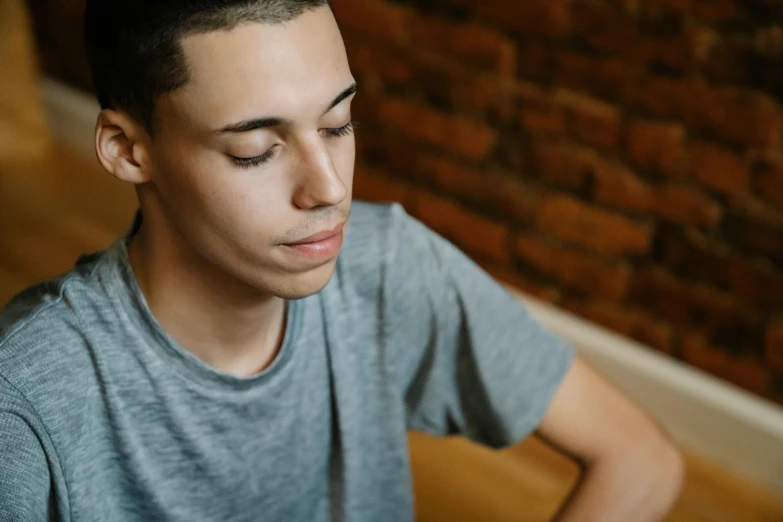 a young man sitting in front of a laptop computer, trending on pexels, hyperrealism, background image, black teenage boy, calm face, grayish