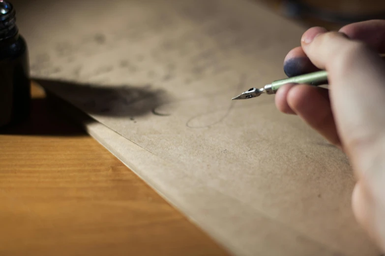 a person writing on a piece of paper with a pen, by Eamon Everall, letterism, parchment paper, blacksad, a wooden, high res photograph