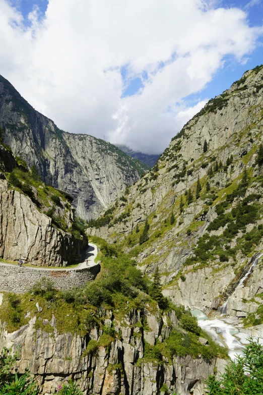 a winding mountain road in the middle of a valley, by Franz Hegi, les nabis, river flowing through a wall, rocks, flume, alp