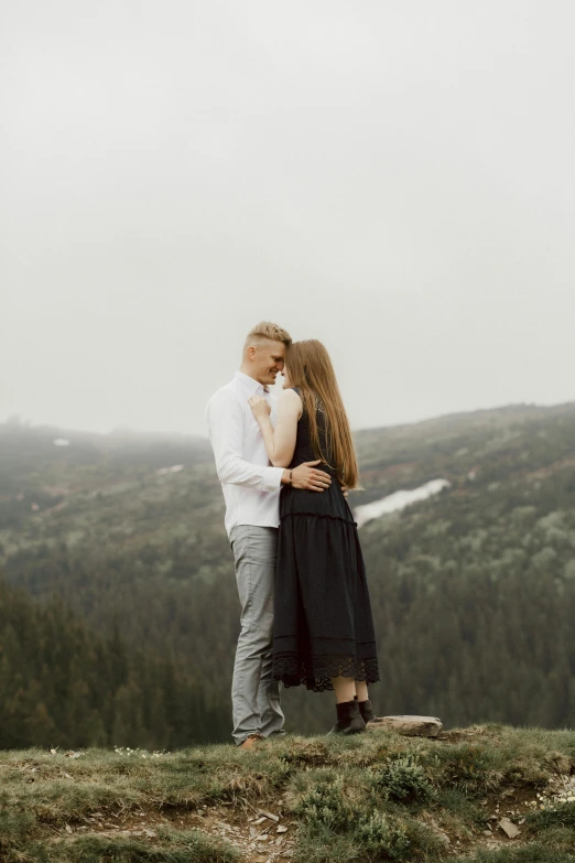 a man and woman standing on top of a hill, pexels contest winner, romanticism, grey forest in the background, making out, low quality photo, mountainous