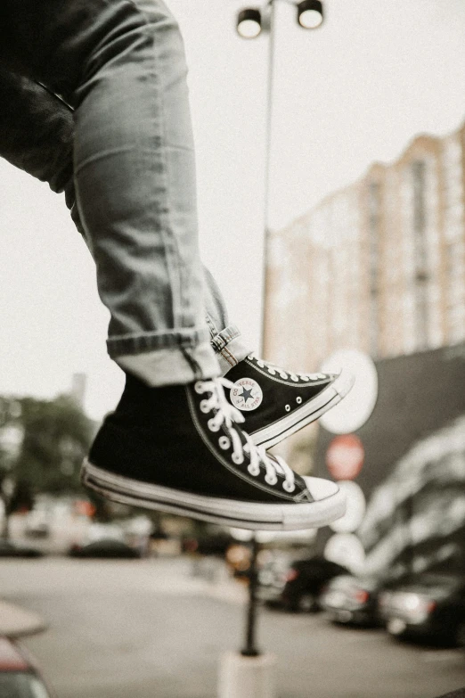 a man flying through the air while riding a skateboard, trending on pexels, realism, converse, whole shoe is in picture, black in, towering