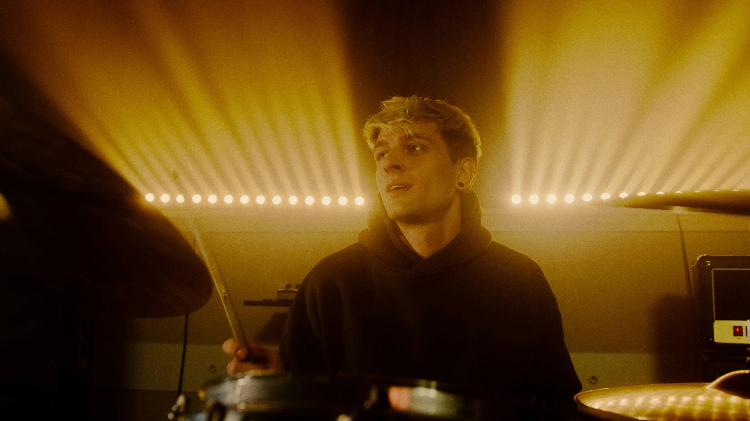 a man playing drums in a dimly lit room, inspired by Oskar Lüthy, yung lean, his eyes glowing yellow, **cinematic, a blond