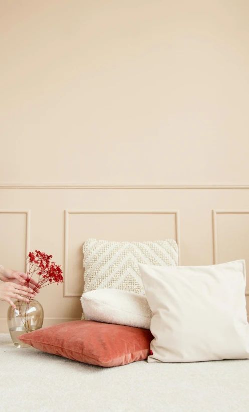 a woman sitting on top of a bed next to pillows, inspired by Wilhelm Hammershøi, trending on pexels, embossed paint, smooth panelling, warm pink living room, cream and white color scheme