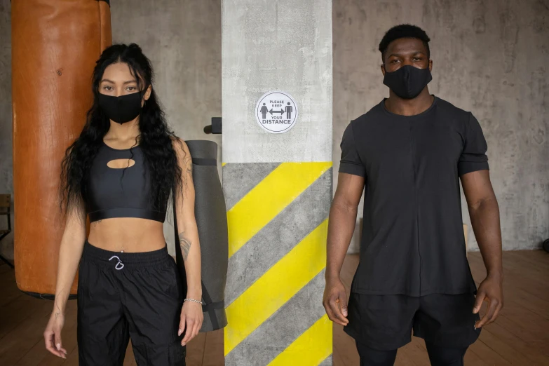 a man and a woman standing next to each other, black facemask, wearing fitness gear, gritty tech, ( ( dark skin ) )