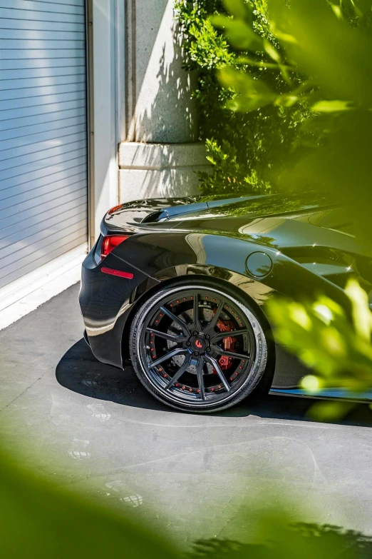 a black sports car parked in front of a garage, inspired by Bernardo Cavallino, pexels contest winner, renaissance, black wheel rims, red tail lights, in gunmetal grey, 2 0 % pearlescent detailing