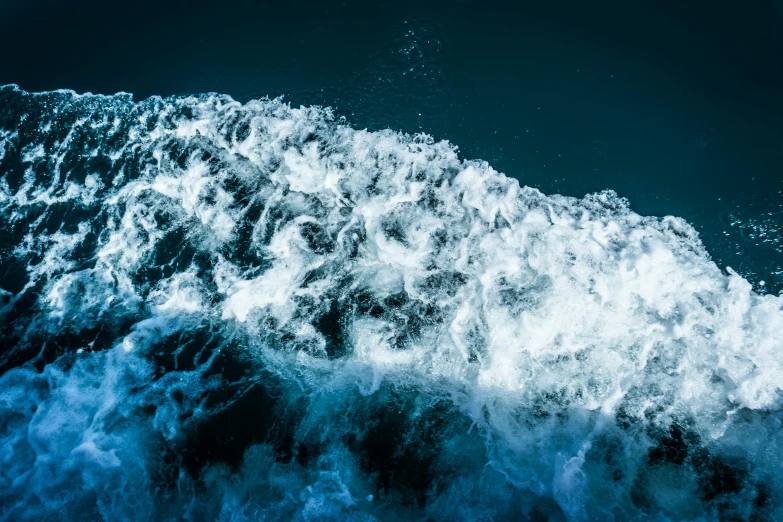 a close up of a wave in the ocean, an album cover, unsplash, hurufiyya, glinting particles of ice, thumbnail, 8k 4k, birdseye view