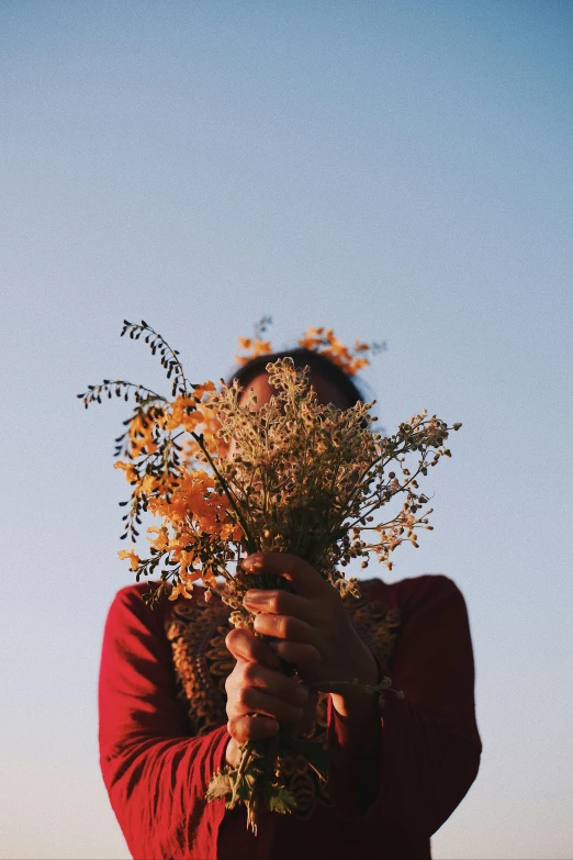 a person holding a bunch of flowers in front of their face, unsplash, cloudless sky, dried plants, beautifully lit, instagram photo