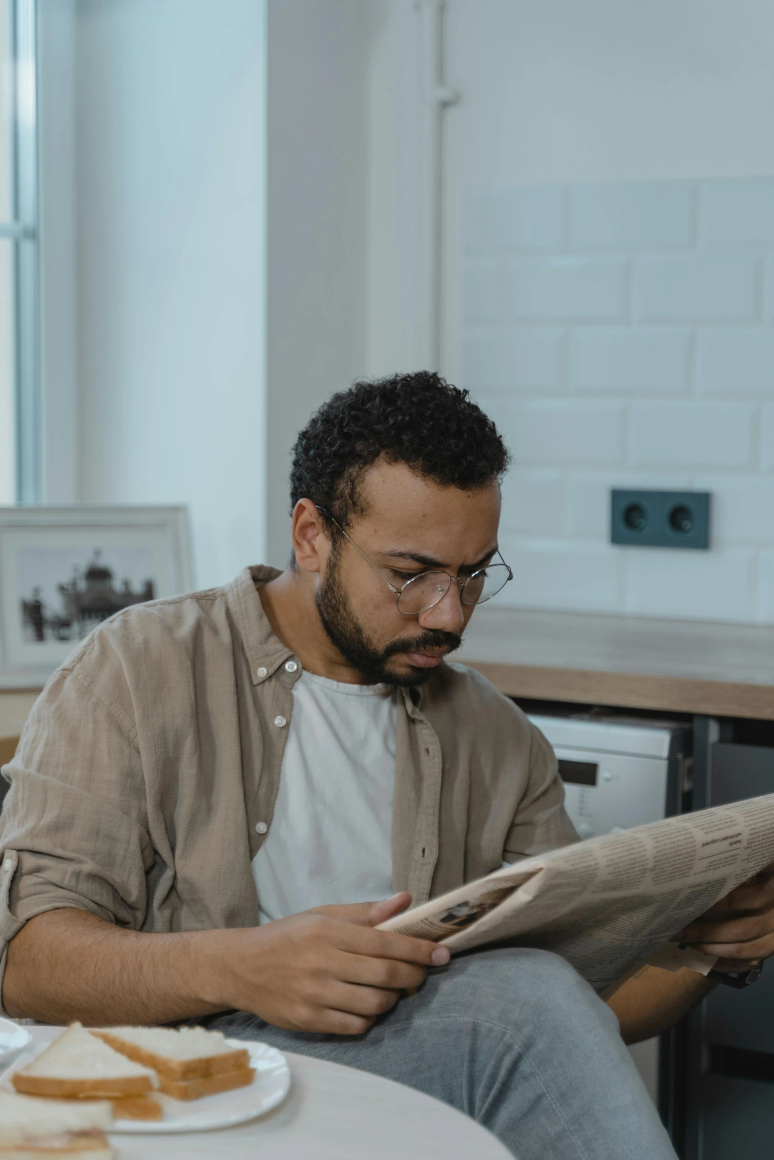 a man sitting at a table reading a newspaper, a cartoon, by Daniel Seghers, pexels contest winner, mixed race, gif, attractive photo, wearing reading glasses