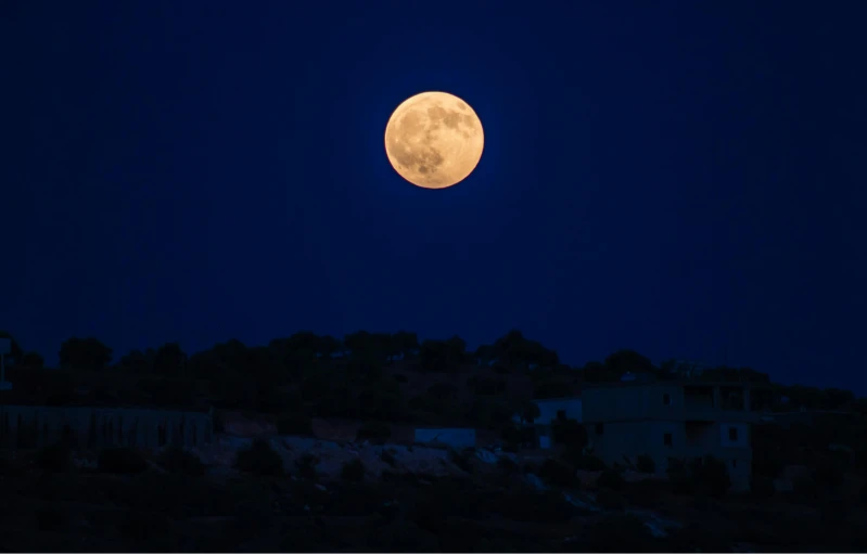 a full moon rising over a small town, an album cover, pexels, cyprus, 2 0 0 mm telephoto, moonshine, 1 2 9 7