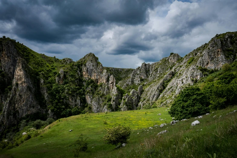 a mountain with green grass and rocks under a cloudy sky, by Muggur, pexels contest winner, les nabis, taras susak, huge chasm, festivals, youtube thumbnail