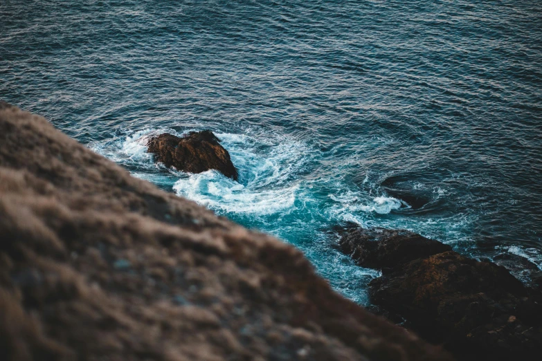 a rock in the middle of a body of water, pexels contest winner, ocean cliff side, turbulent water, telephoto shot, youtube thumbnail