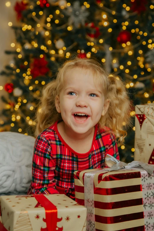 a little girl sitting in front of a christmas tree with presents, pexels contest winner, incoherents, happily smiling at the camera, avatar image, 4k image, zoomed in