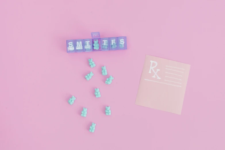 a piece of paper sitting on top of a pink surface, vials, cute teeth, blue translucent resin, candy hospital room