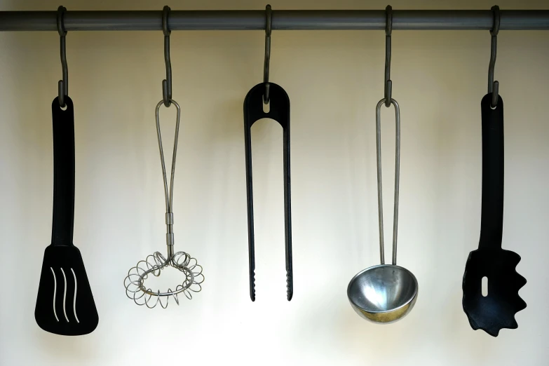 a collection of kitchen utensils hanging on a wall, inspired by Marcel Duchamp, bauhaus, neck shackle, high quality product image”, 3 heads, closeup - view