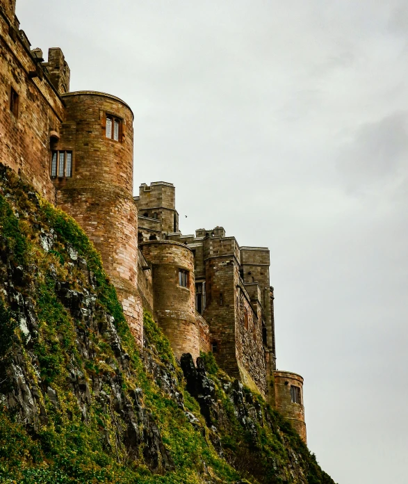 a large castle sitting on top of a lush green hillside, an album cover, by John Gibson, pexels contest winner, side view intricate details, city wall, greaves, thumbnail