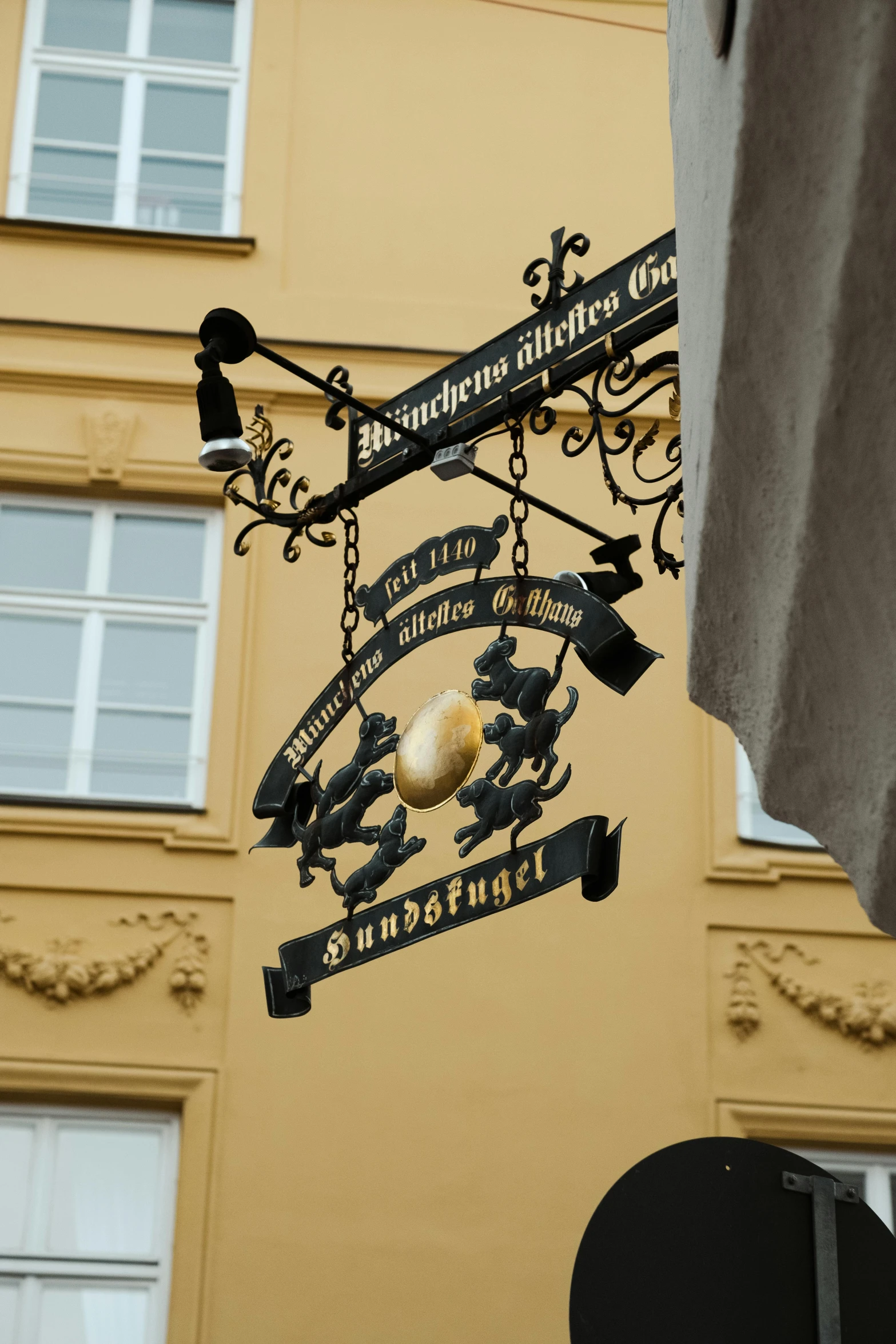 a street sign hanging from the side of a building, inspired by Mihály Munkácsy, gold decorations, gas lamps, delightful surroundings, sigil