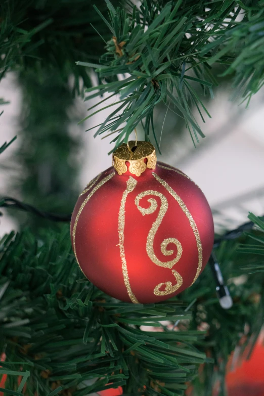 a red ornament hanging from a christmas tree, inspired by Ernest William Christmas, art nouveau, gold striated swirling finish, medium close shot, subtle detailing, medium - shot