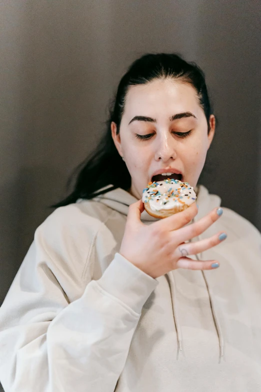a woman taking a bite out of a doughnut, trending on pexels, wearing a hoodie and sweatpants, bun, white, gif