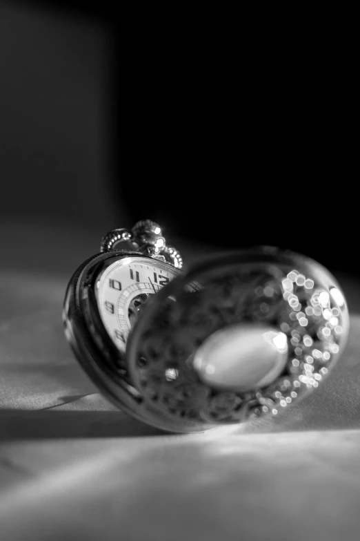 a pocket watch sitting on top of a bed, a black and white photo, flickr, platinum jewellery, profile picture 1024px, silver，ivory, amulet