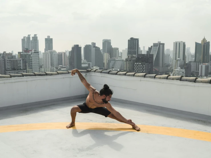 a man doing a yoga pose on top of a building, inspired by Kanō Tan'yū, pexels contest winner, arabesque, singapore, square, low quality photo, body format