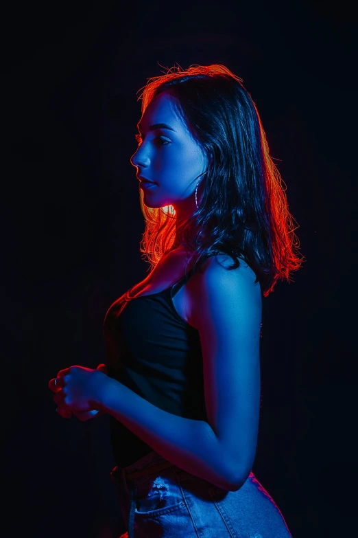 a woman standing in front of a black background, inspired by Elsa Bleda, blue and red lighting, highkey lighting, blue and orange lighting, back light contrast