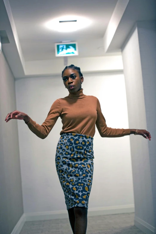 a woman standing on a skateboard in a hallway, an album cover, by Lily Delissa Joseph, patterned clothing, pencil skirt, ( ( dark skin ) ), 2 4 year old female model