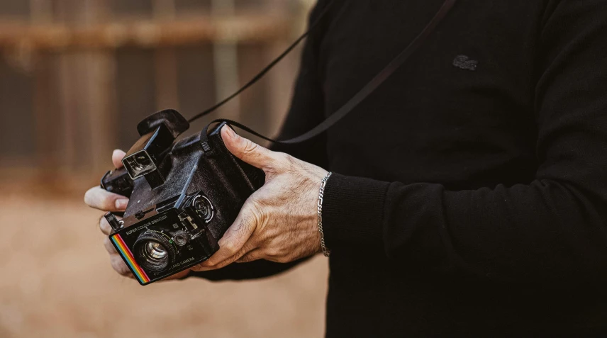 a close up of a person holding a camera, by Peter Churcher, worn, medium format, desert photography, nostalgic 8k