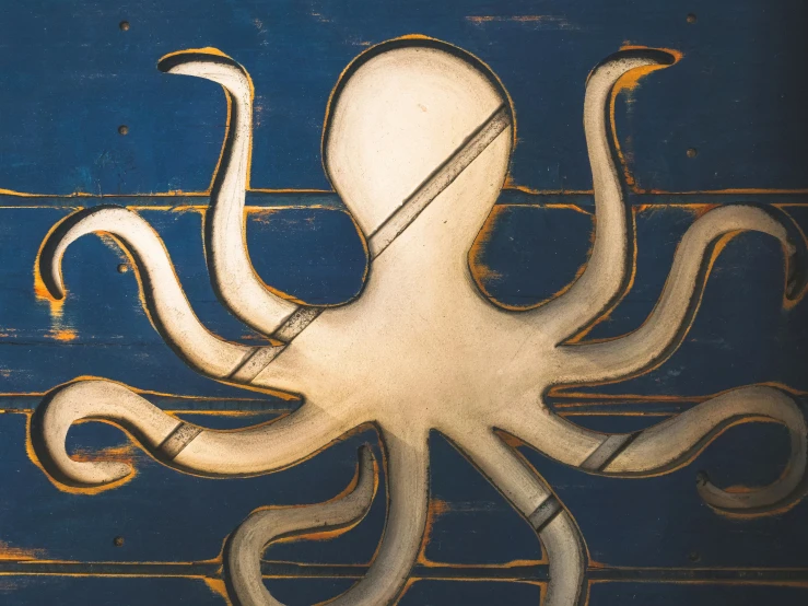 a close up of an octopus on a wall, an album cover, by John Murdoch, unsplash, carved in wood, navy, four arms, industrial art style