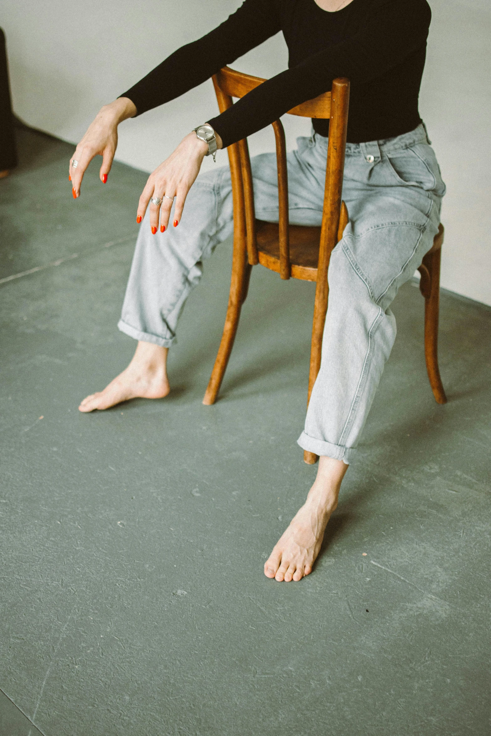 a woman sitting on top of a wooden chair, by Nina Hamnett, unsplash, renaissance, the forefoot to make a v gesture, wearing cargo pants, studio floor, worn out