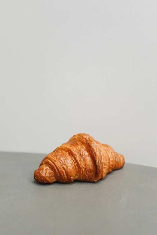 a close up of a croissant on a table, by Tom Bonson, on a gray background, an ultra realistic, cone shaped, bust