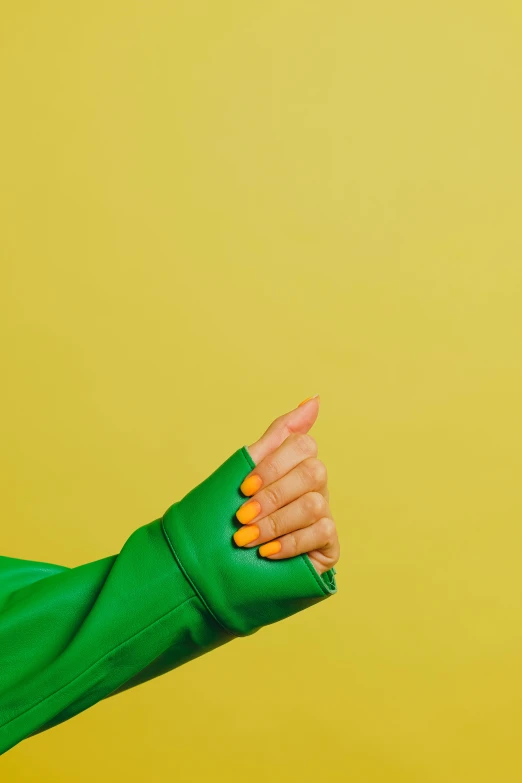 a person in a green shirt pointing at something, by Olivia Peguero, trending on pexels, aestheticism, glossy yellow, wearing jacket, long nails, clemens ascher